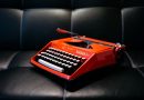 rote Schreibmaschine auf schwarzer Couch
