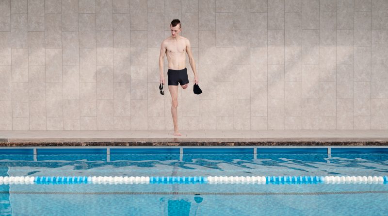 Mann mit einem Bein steht am Rand eines Schwimmbeckens