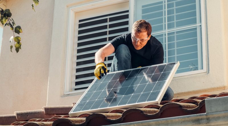 ein Mann installiert eine Photovoltaik-Anlage auf einem Dach