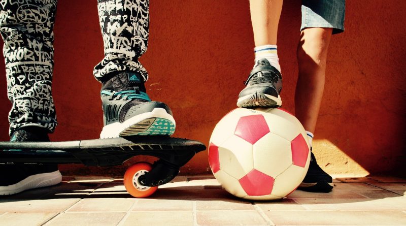 Beine mit Skateboard und Fußball